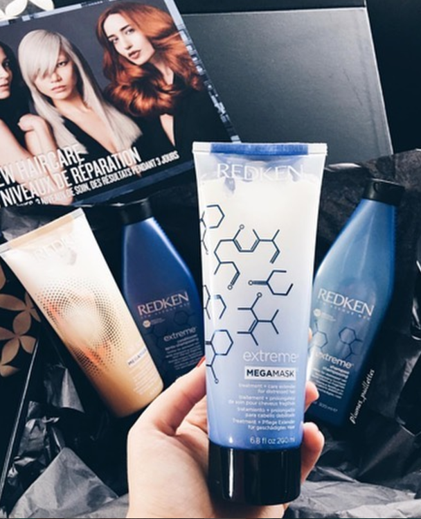 Hand holding up a blue tube of Redken Extreme Mega Mask.